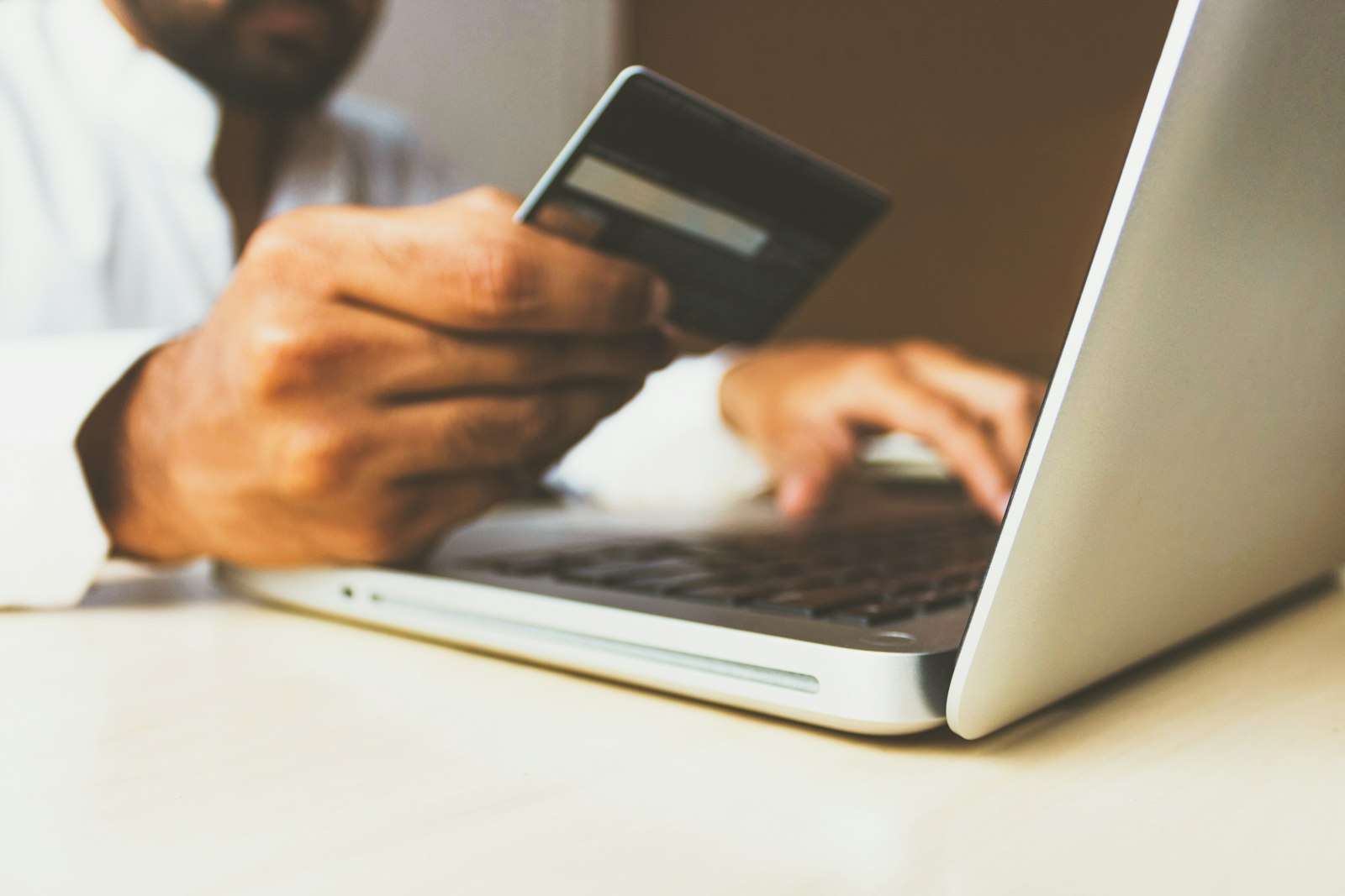 A person using a laptop computer while holding a card, representing a credit and loan application review